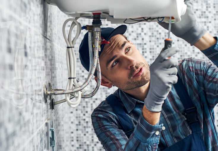 Plombier répare un lavabo qui fuie